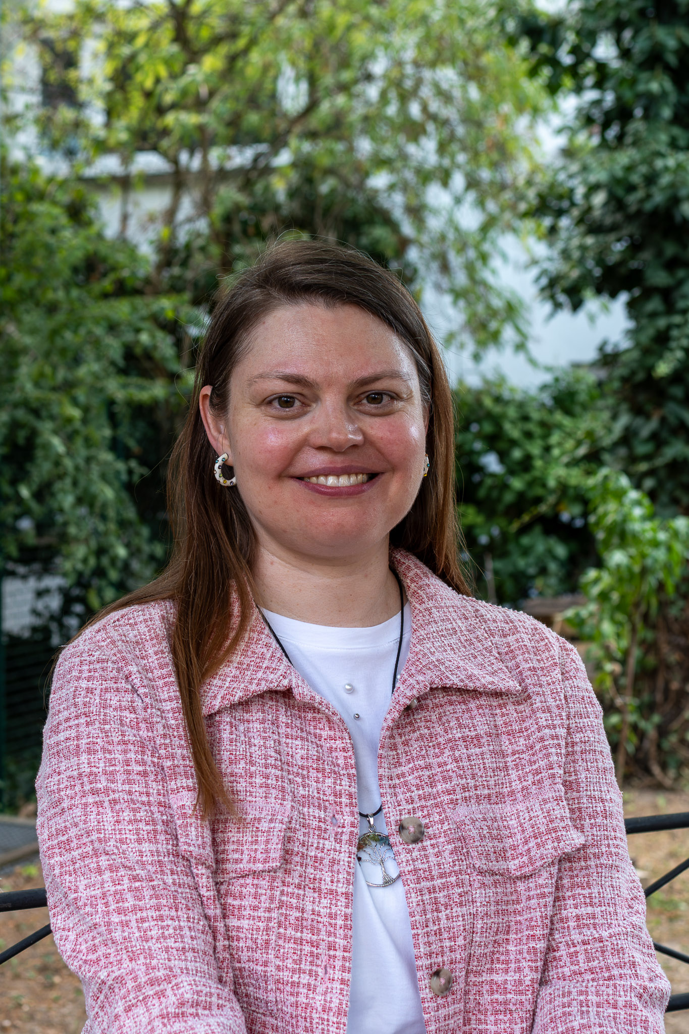 Das Bild zeigt eine Frau mit langen, offenen Haaren. Sie trägt einen pinken Blazer.